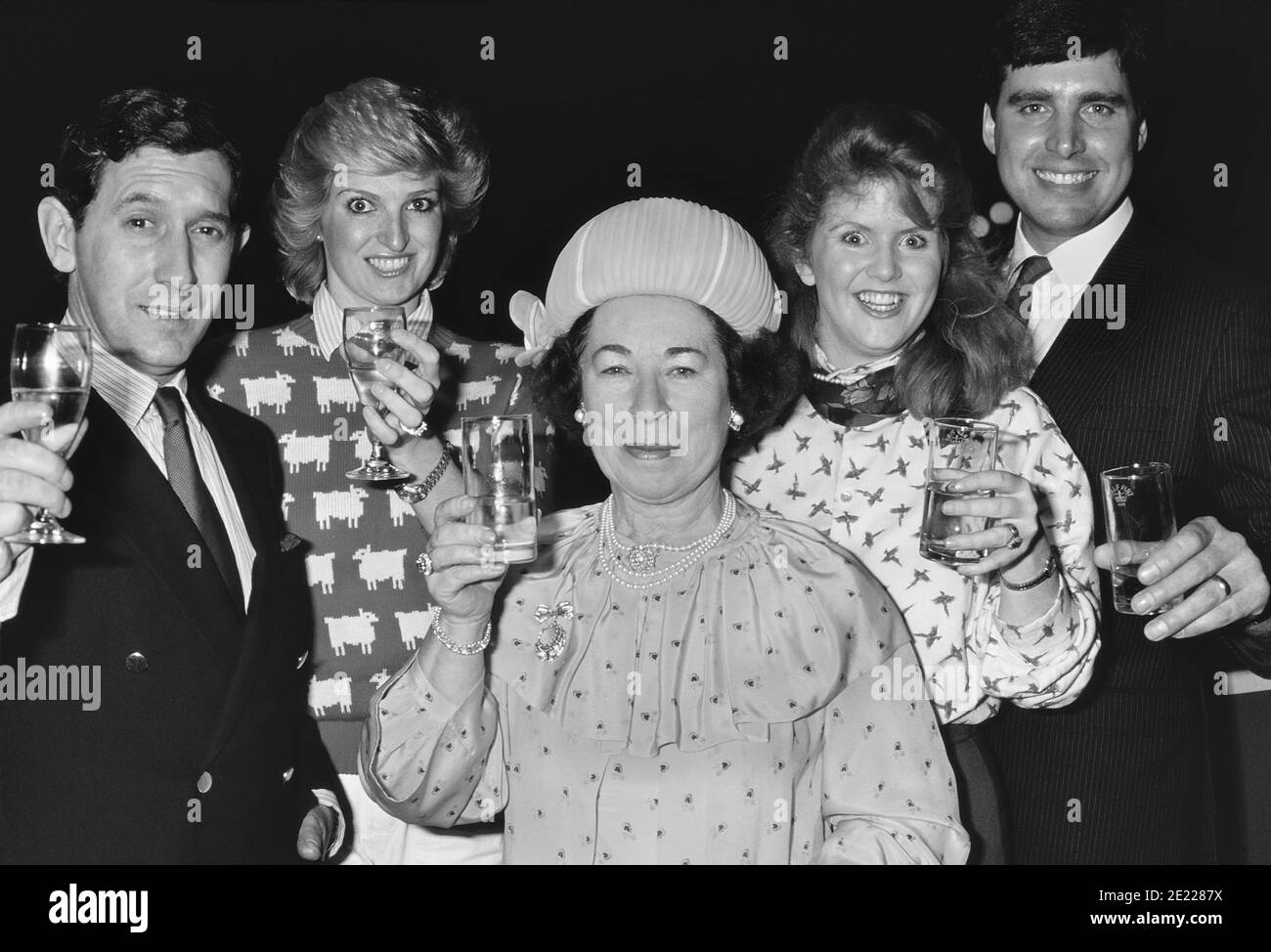 Un gruppo di "Royal Family Look-a-like" britannici alzano i loro occhiali verso la fotocamera. Circa anni '80 Foto Stock