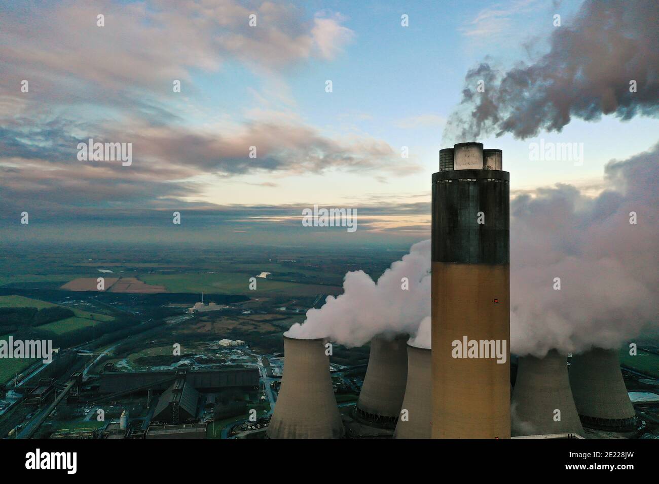 Un'immagine aerea della cima di un carbone sparato Camino della centrale elettrica che emette anidride carbonica inquinante nella parte superiore atmosfera con spazio per la copia Foto Stock