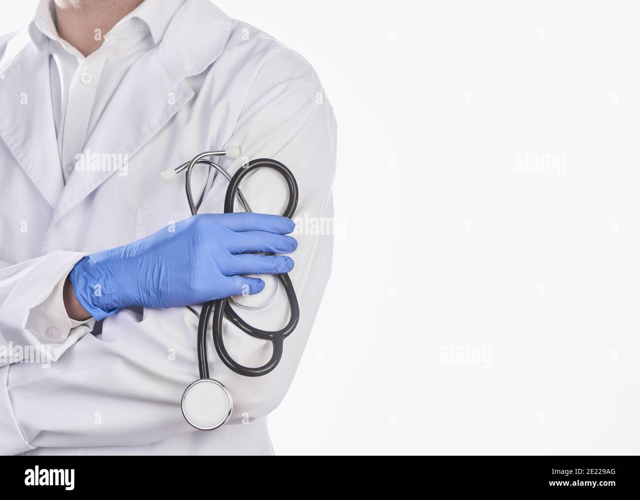 Medico indossando camice e guanti bianchi, tenendo uno stetoscopio su sfondo bianco Foto Stock