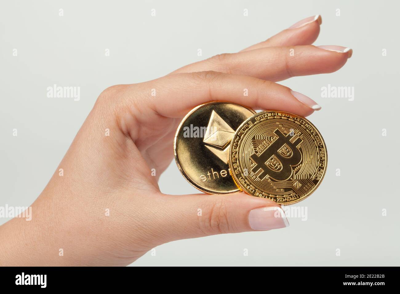 mano femmina macro che tiene il bitcoin e l'etereo fianco a fianco concetto di criptovaluta Foto Stock