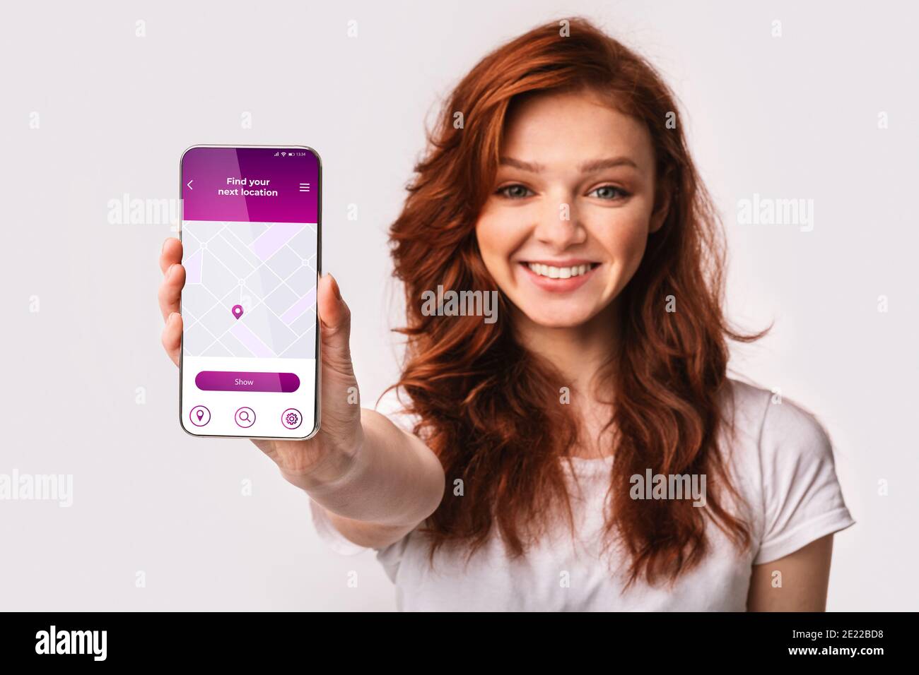 Allegra donna Redhead che mostra smartphone con l'app di navigazione GPS aperta Sullo schermo Foto Stock