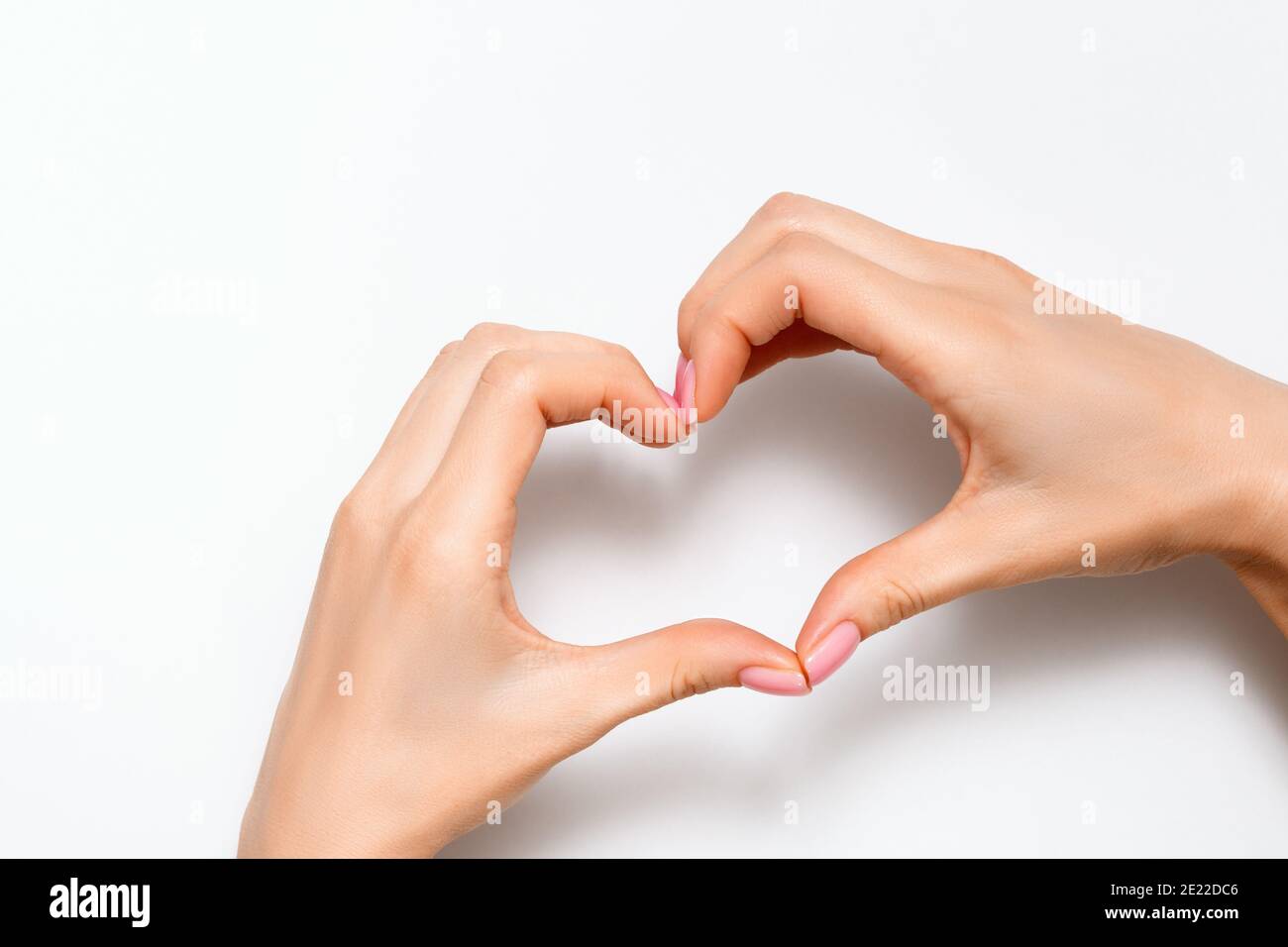 Giovane donna con le mani mostra un segno del cuore su uno sfondo grigio. Concetto per il giorno di San Valentino, amore, romatica. Spazio di copia vista dall'alto. Foto Stock