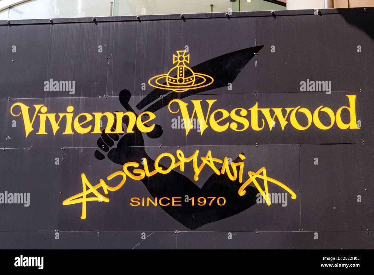Primo piano del logo sopra il negozio del logo Vivienne Westwood Anglomania sul suo negozio di punta a Harujuku. Tokyo. Lettere gialle su nero. Foto Stock