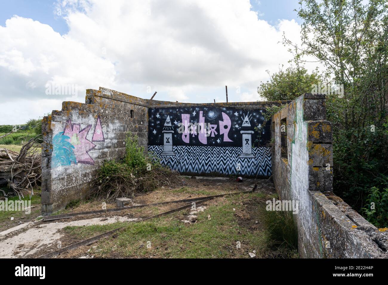 Abbandonato edificio derelict in un campo di pecore, l'ex guerra mondiale Richborough una prigione, centro di detenzione. Strani graffiti alieni moderni sulla parete. Foto Stock