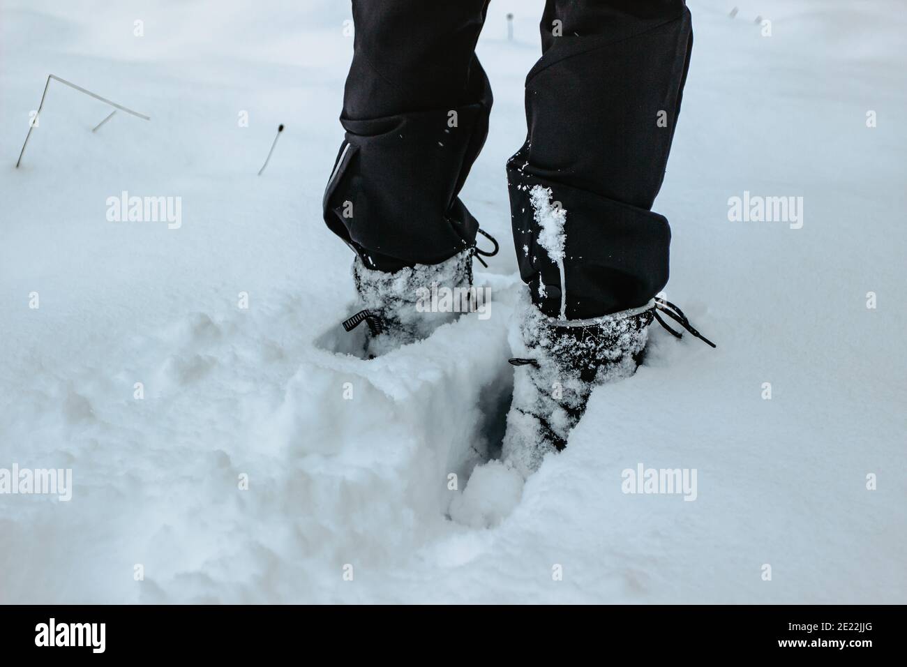 Dettaglio di stivali caldi impermeabili in neve fresca profonda.piedi femminili in scarpe nere, passeggiata invernale in neve.Vista ad angolo basso di gambe in piedi femmina con neve Foto Stock