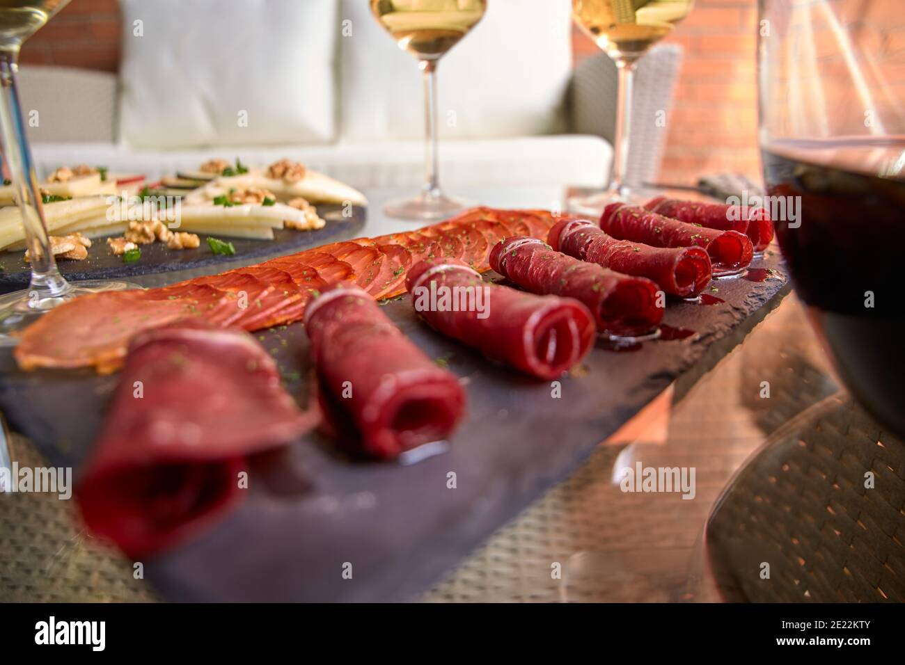 Piatto di ardesia con prosciutto e salumi accompagnati da bicchieri di vino Foto Stock