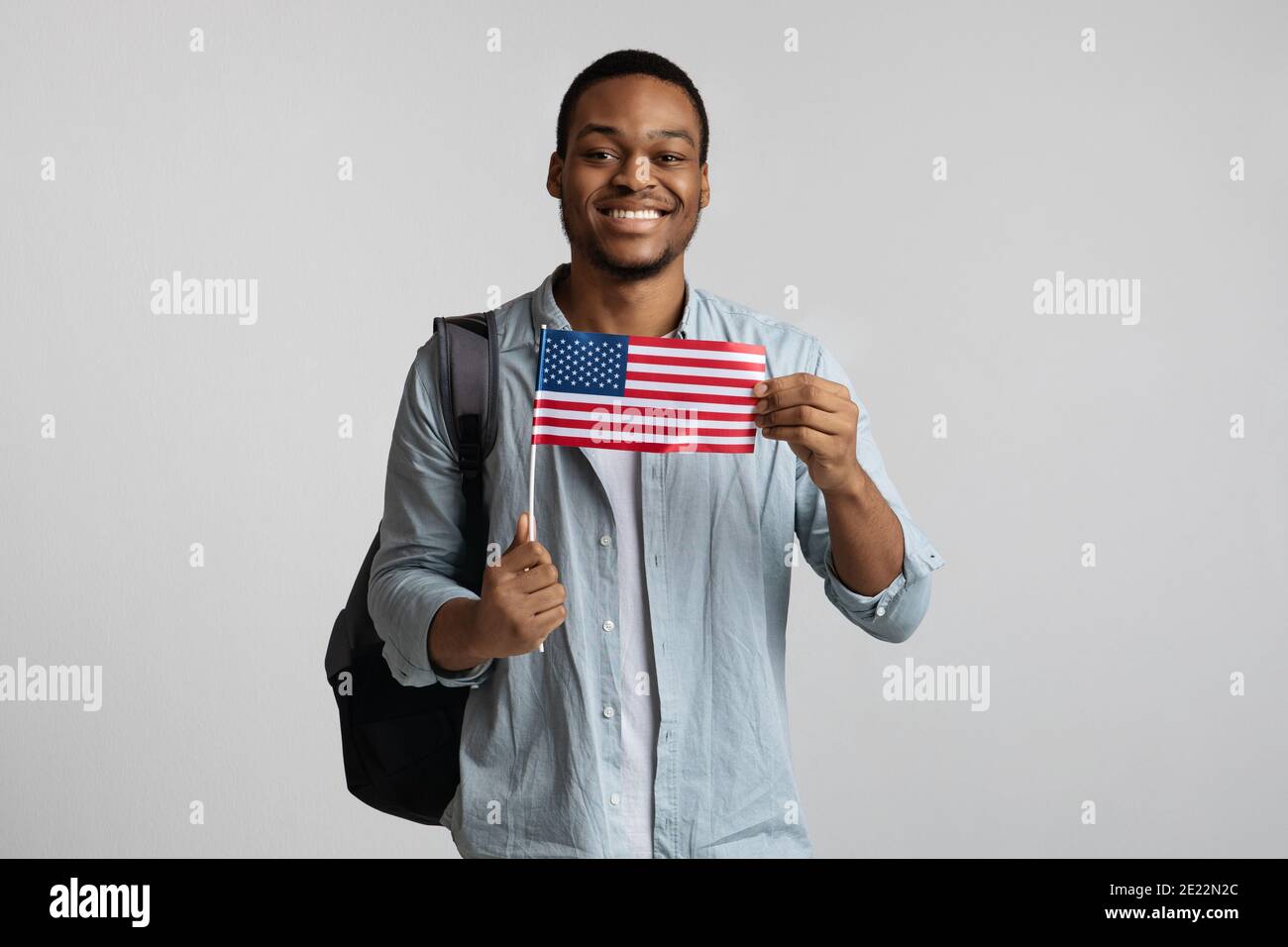 Ragazzo nero positivo con zaino che tiene bandiera americana Foto Stock