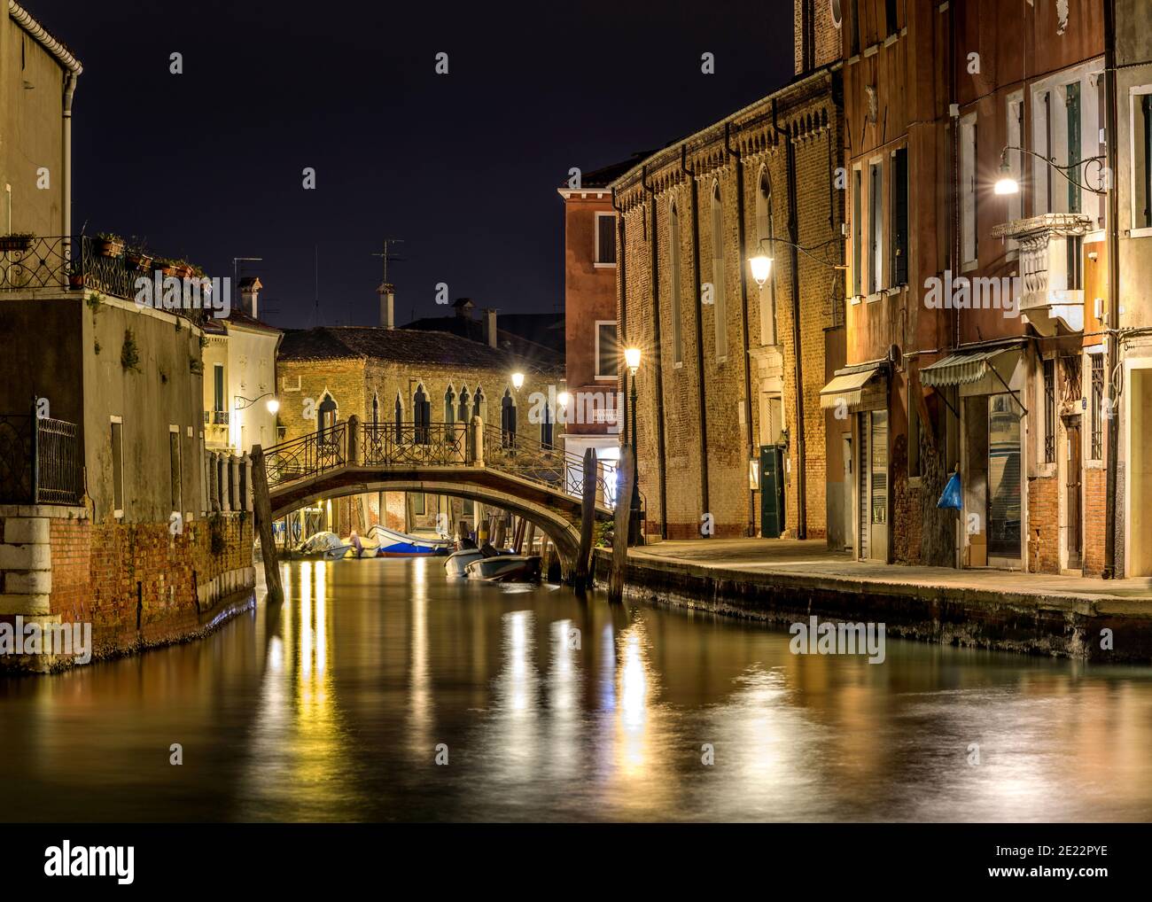 Notte a Murano - Vista notturna di un piccolo ponte di mattoni, Ponte San Pietro Martire, che attraversa uno stretto corso d'acqua, al centro di Murano, Italia. Foto Stock