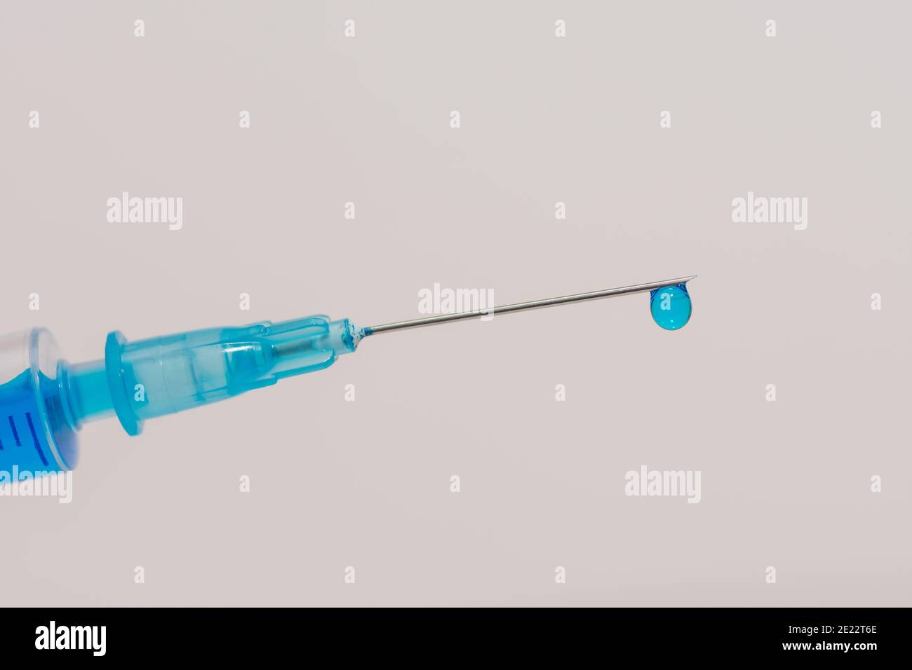 siringa con un vaccino fluido blu e una goccia su vista frontale con sfondo bianco Foto Stock