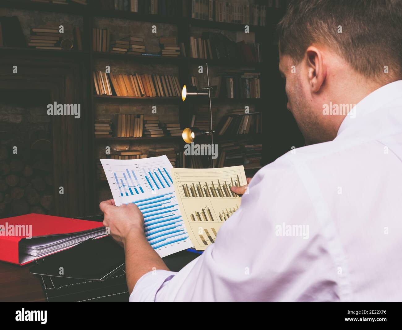 Un uomo d'affari lavora a tarda notte con documenti e relazioni finanziarie. Foto Stock