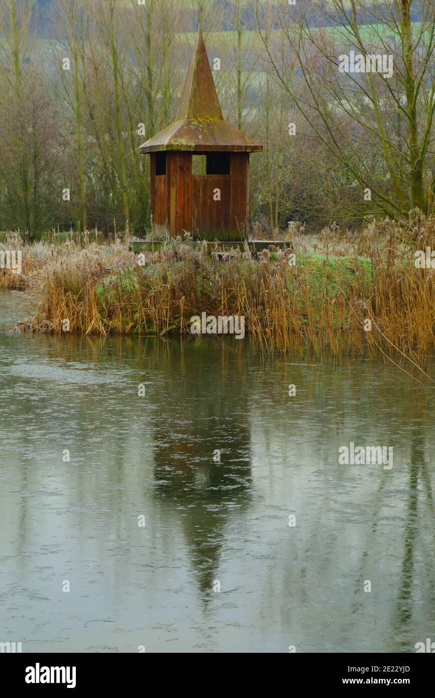 Il cuoio di bird watching di legno riflesso sul lago in Devon, Regno Unito Foto Stock