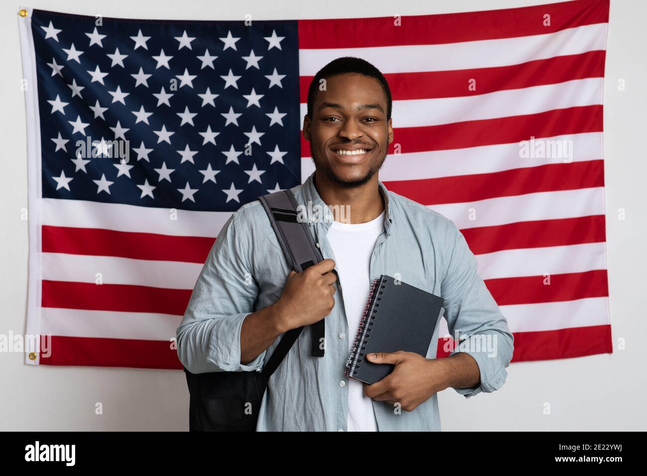 Allievo sorridente dell'uomo nero che si trova sopra la bandiera americana Foto Stock