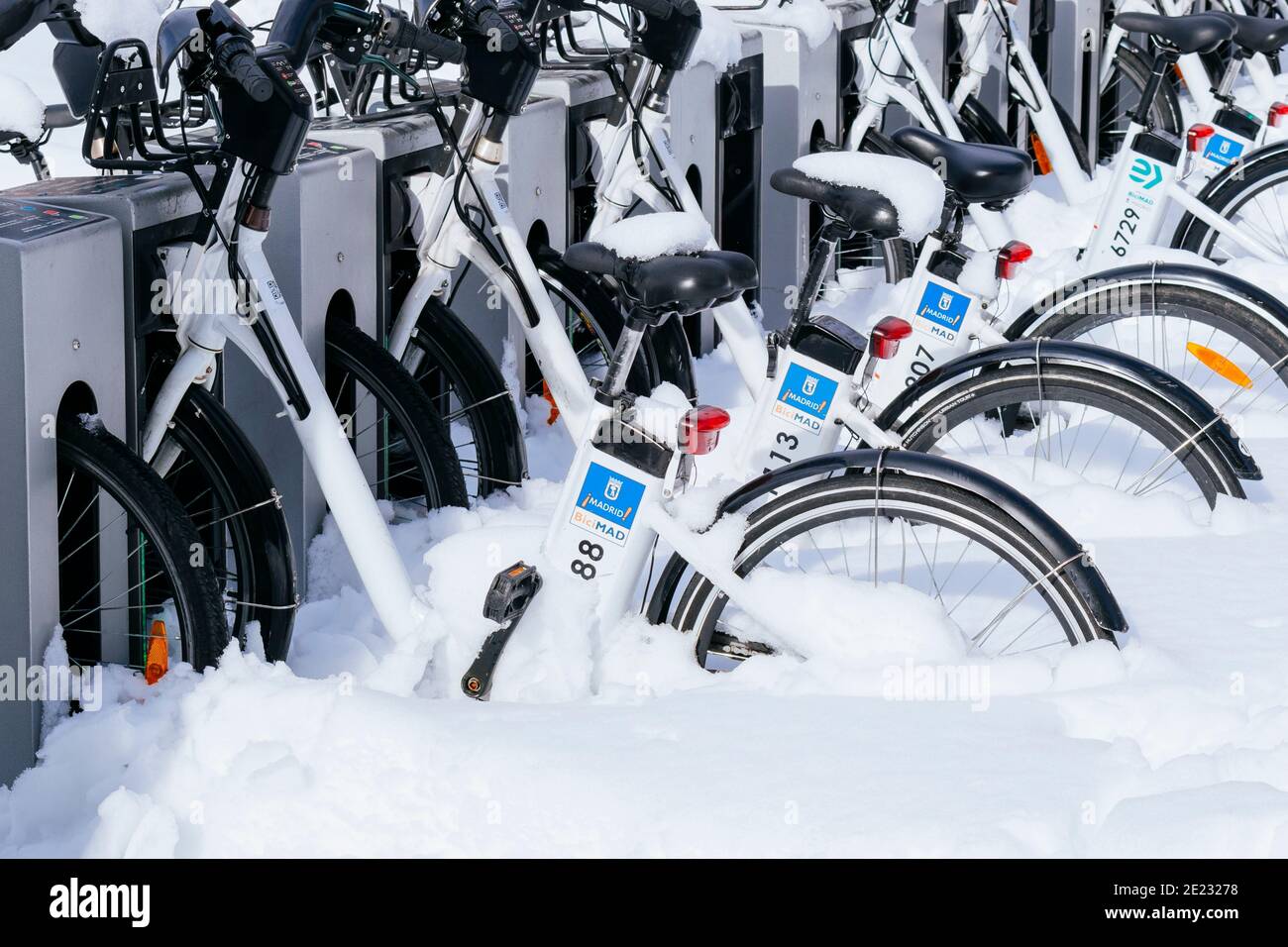 Biciclette del servizio comunale di Madrid, BICIMAD, coperto di neve parcheggiata in stazione. Il giorno dopo Filomena nevicata pesante. Madrid, Spagna Foto Stock