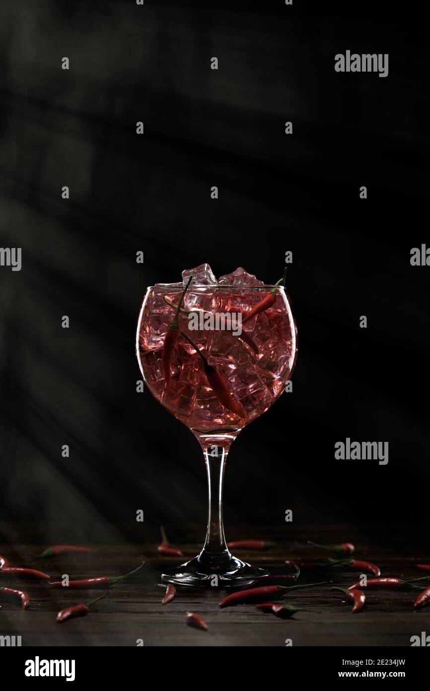 Cocktail rosso in un bicchiere con ghiaccio e peperoncini. Concetto di San Valentino Foto Stock