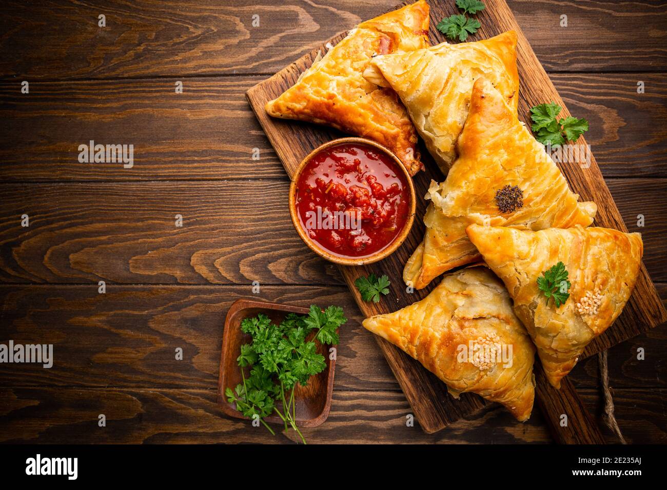 Samsa o samosa con carne e verdure con salsa di pomodoro su fondo ligneo. Cucina asiatica tradizionale. Vista dall'alto. Foto Stock