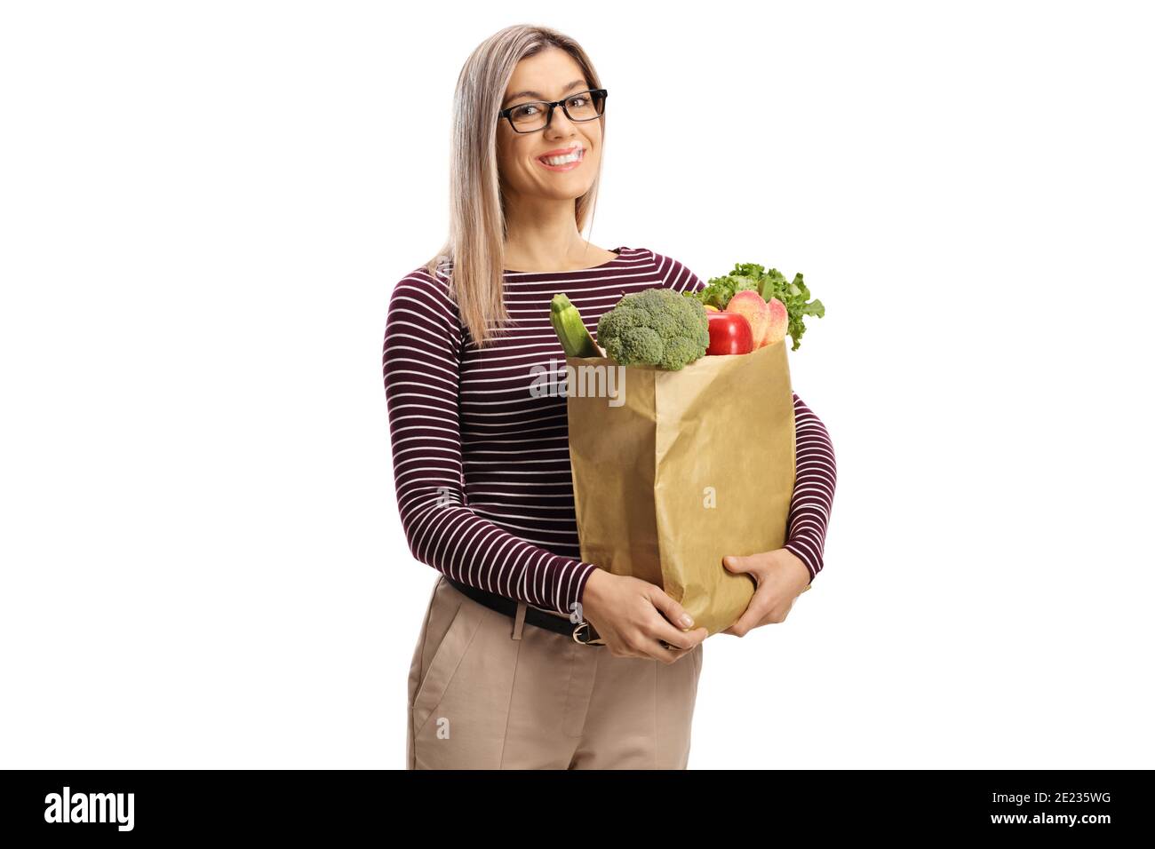 Donna bionda con occhiali che portano una borsa di carta con generi alimentari isolato su sfondo bianco Foto Stock