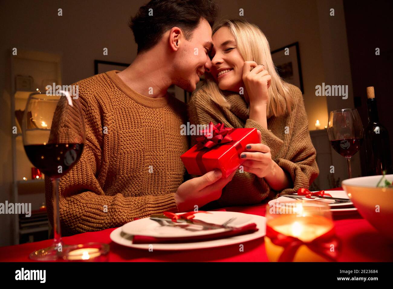 L'uomo amorevole che dà scatola regalo rossa abbracciando la donna amata o giorno di San Valentino. Foto Stock