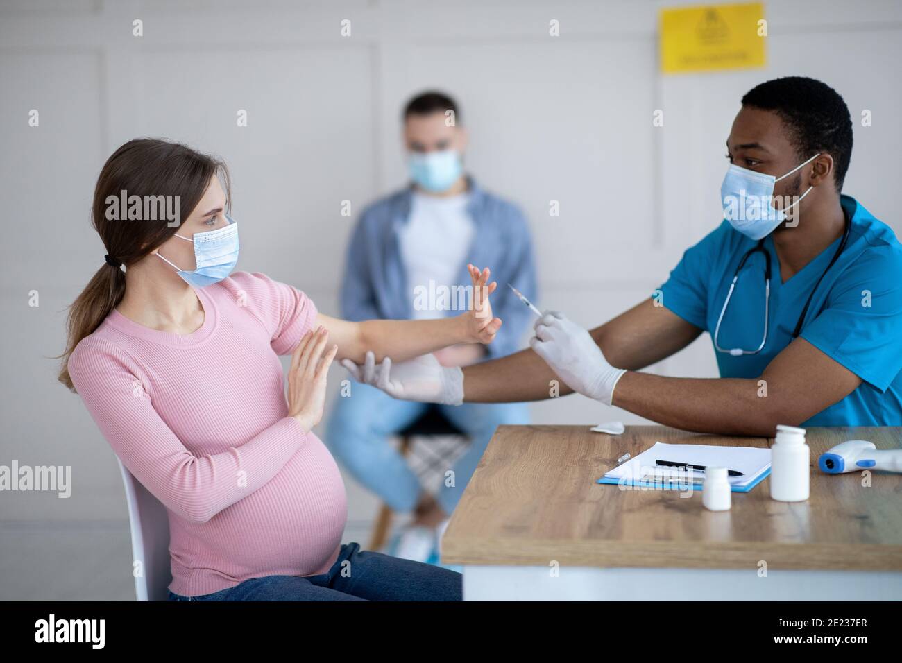 Donna incinta spaventata che rifiuta l'iniezione del vaccino del coronavirus in clinica. Concetto di sanità e medicina Foto Stock