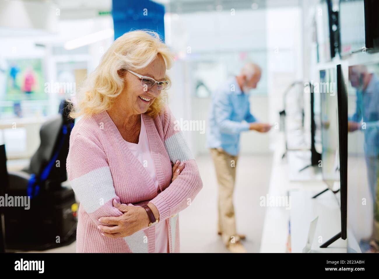 Bel ritratto di donna anziana al negozio di tecnologia. Alla ricerca di una nuova Smart TV. Foto Stock