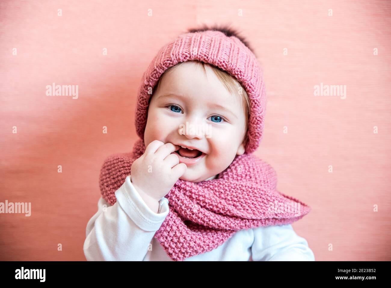 Ragazza capelli lunghi sogno sfondo rosa. Accessorio in maglia da uomo da sogno per bambini. La ragazza del capretto indossa il cappello e l'accessorio alla moda della maglia cute della sciarpa. Foto Stock