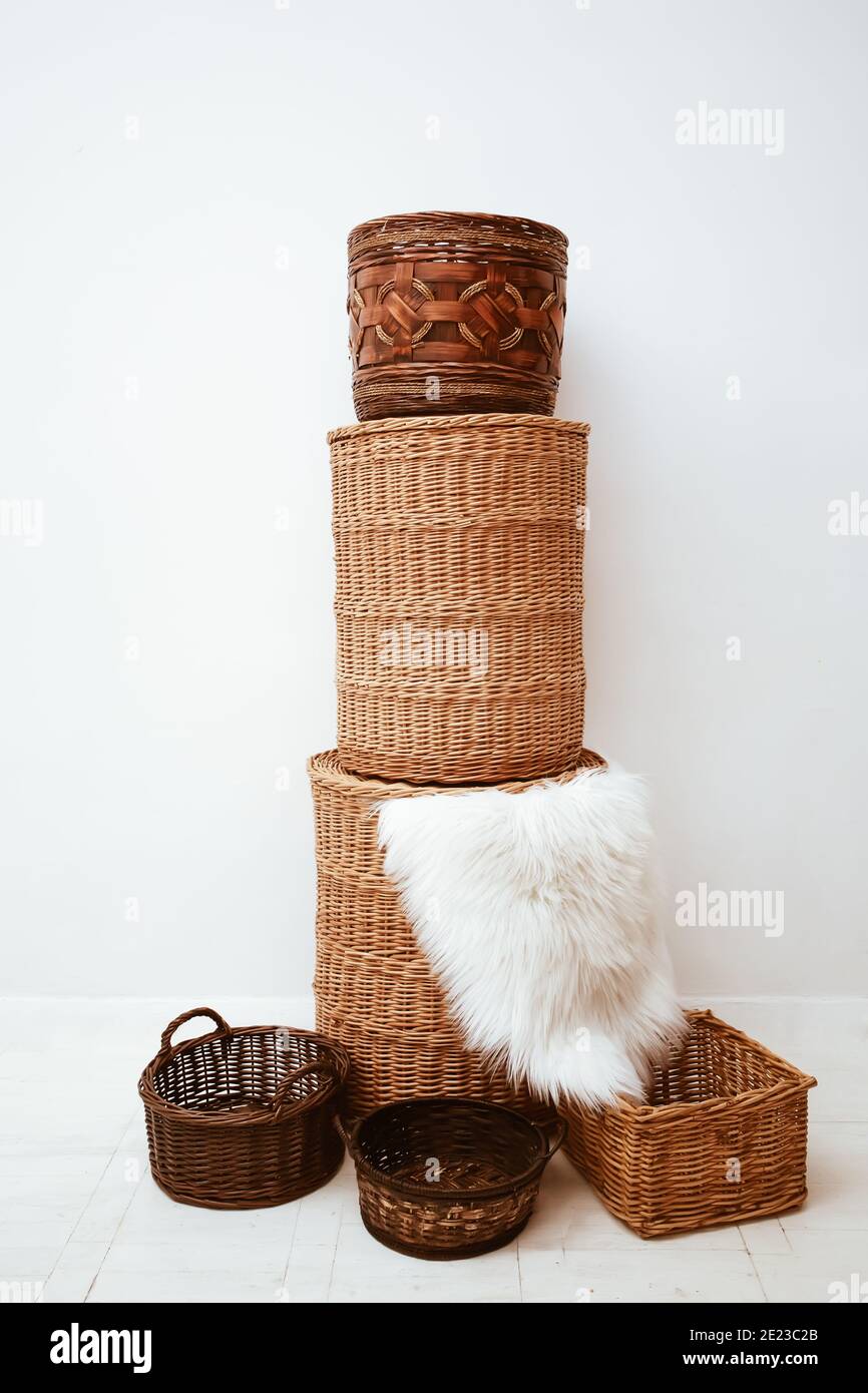 Stack di eleganti cestini di paglia di vimini fatti a mano per lo stoccaggio a casa, bel decor interno con soffice tappeto su sfondo bianco Foto Stock