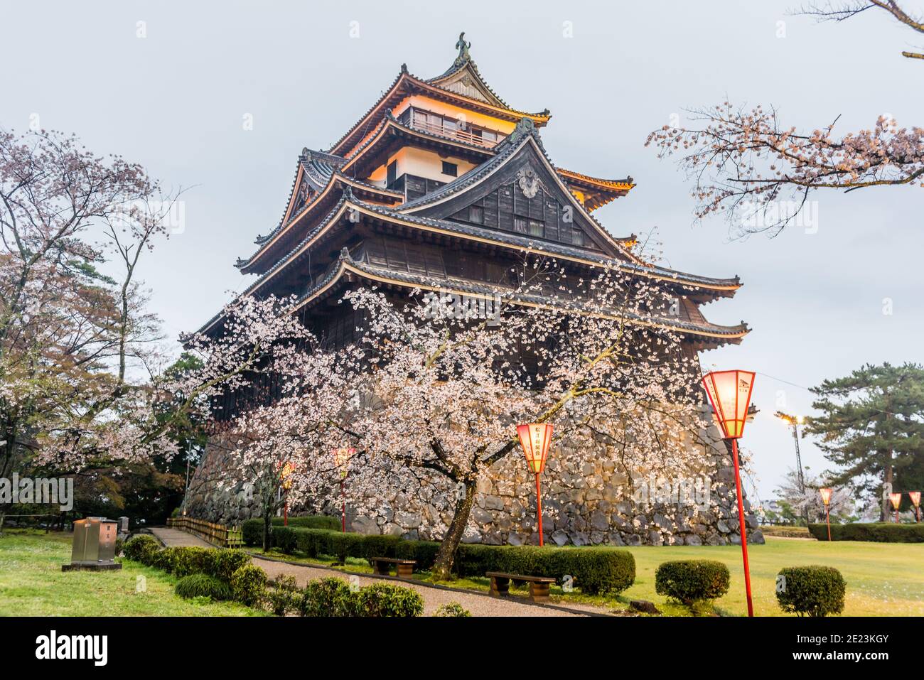 Matsue Castello con il suo giardino e lanterne giapponesi su un giorno nuvoloso Foto Stock