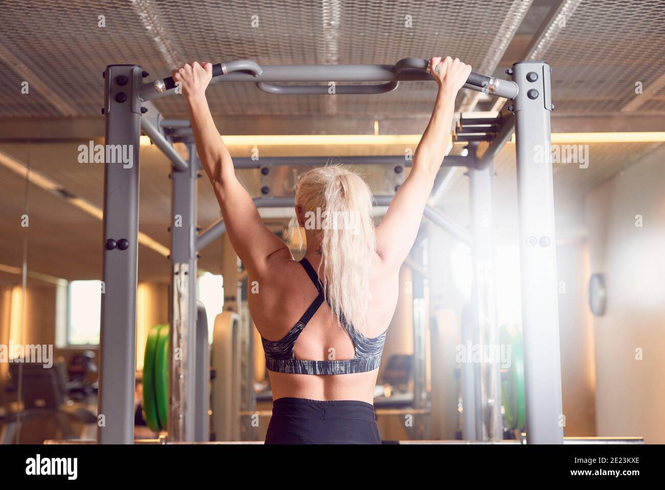 Vista posteriore dell'atleta femminile anonima che fa tirare su bar durante l'allenamento in palestra Foto Stock