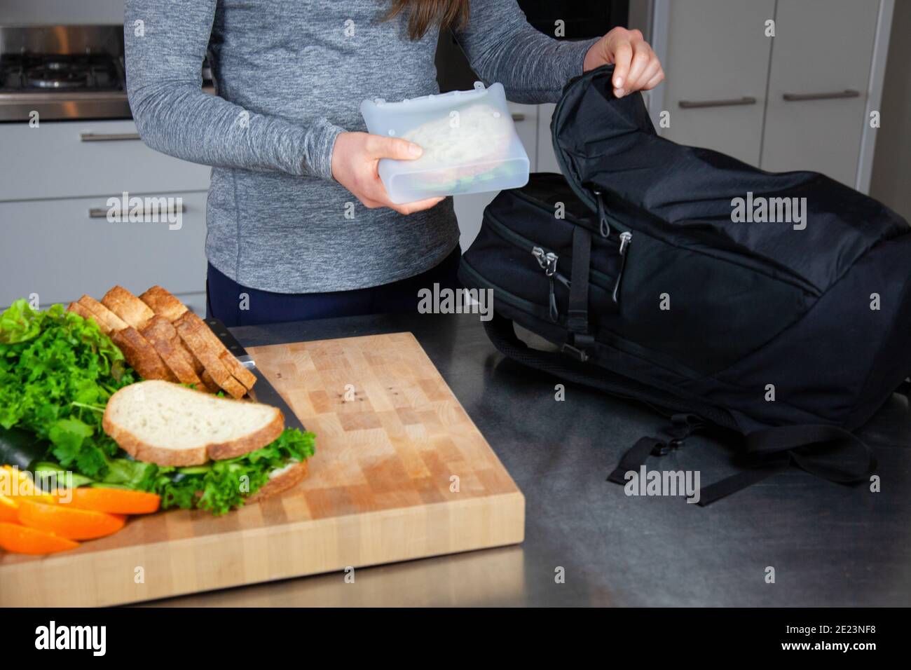 Una donna prepara il pranzo e mette un panino in un sacchetto in silicone per alimenti come parte di uno stile di vita senza sprechi a. sostituire i sacchetti di plastica Foto Stock