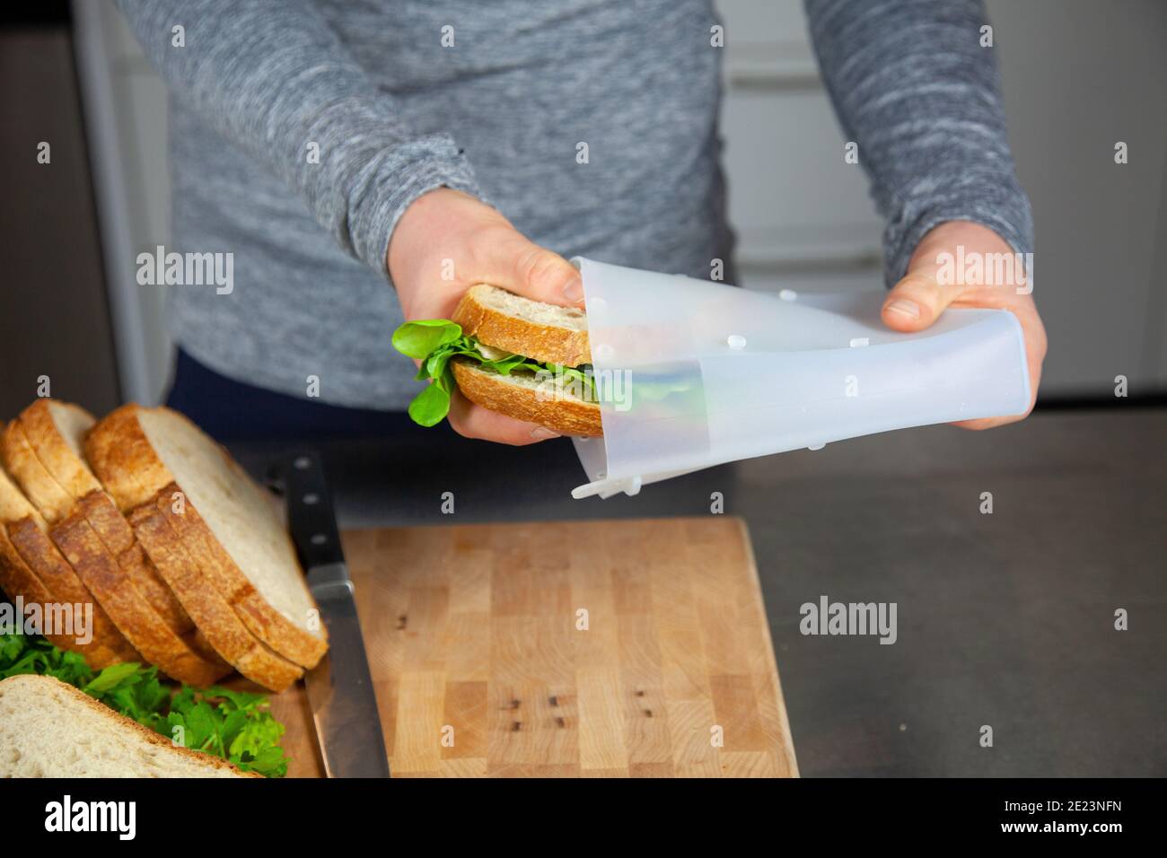Una donna prepara il pranzo e mette un panino in un sacchetto in silicone per alimenti come parte di uno stile di vita senza sprechi a. sostituire i sacchetti di plastica Foto Stock