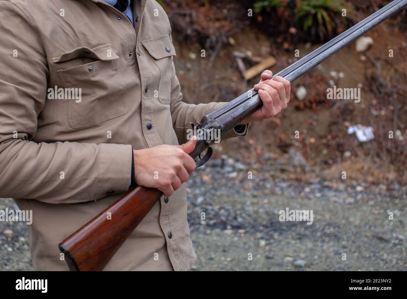 Un uomo tiene un vecchio, antico, fucile a doppio cilindro alla sua vita, indicando il barile downrange, pronto per il caricamento. Campo di azione all'aperto a Squamish, British-Colu Foto Stock