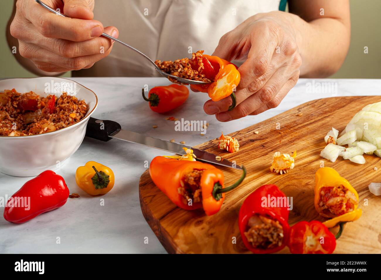 Una chef donna sta riimbottendo i peperoni usando un cucchiaio di metallo. Ha riso ripieno di cipolle, carne macinata, pomodoro, erbe, spezie. Si tratta di un Turco tradizionale Foto Stock
