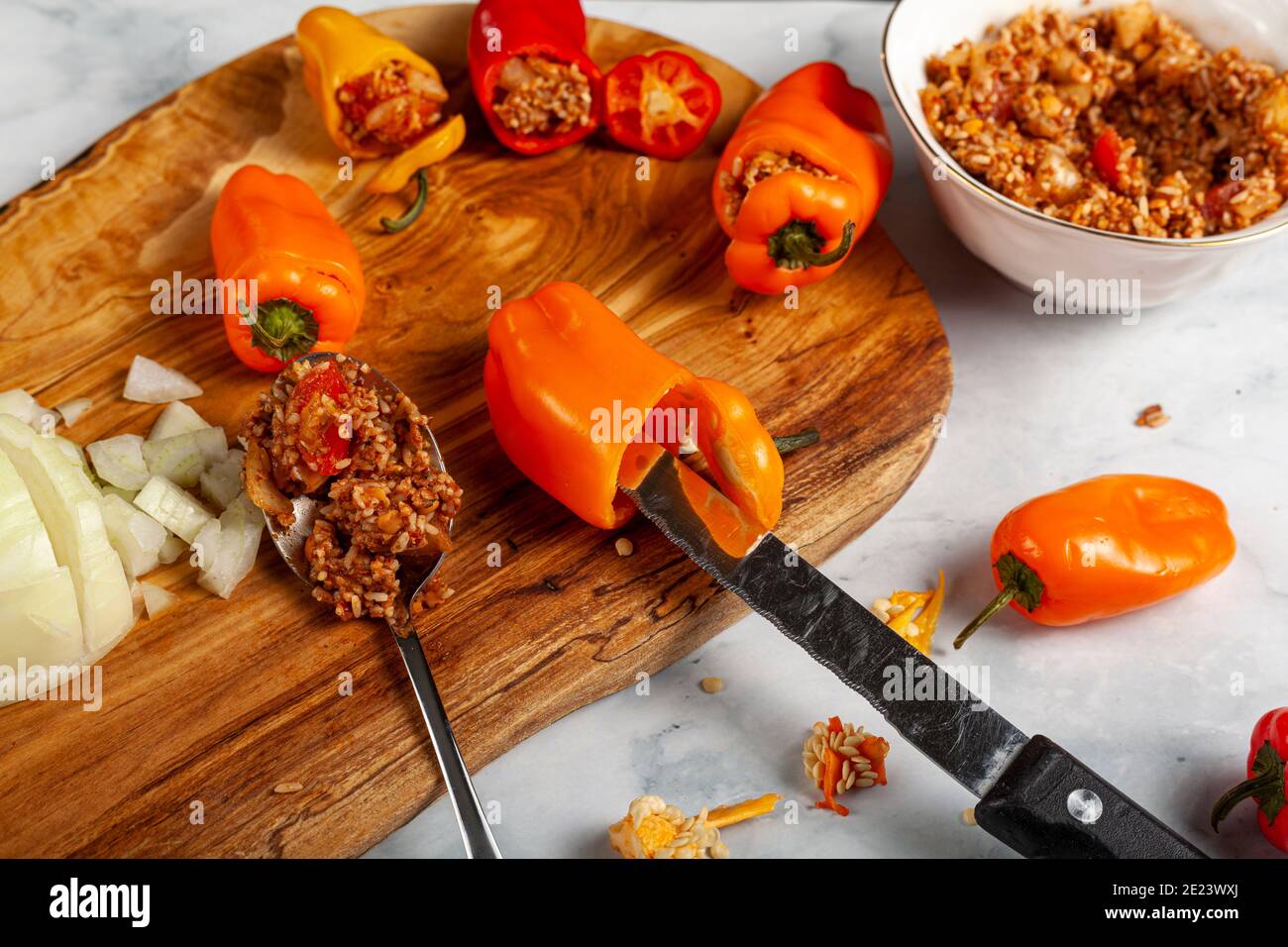 Preparazione di peperoni ripieni con peperoni colorati rossi e gialli con semi prelevati a coltello e ripieno di riso, carne, cipolla tagliata a dadini, Foto Stock