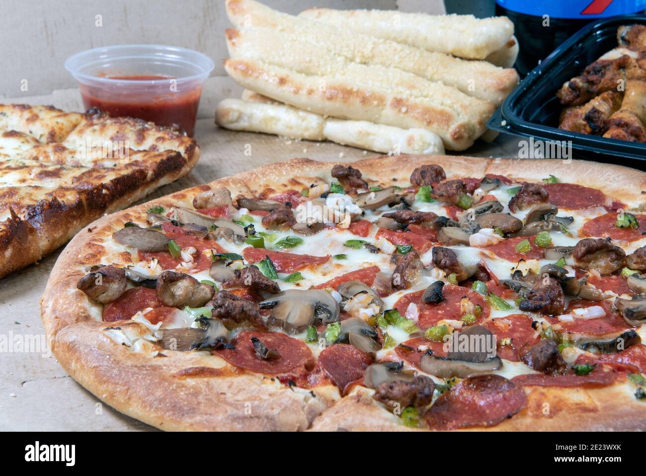 Tavola completa di cibo che include pizza, grissini, pane al formaggio, salsa piccante, ali di pollo e bevande. Foto Stock