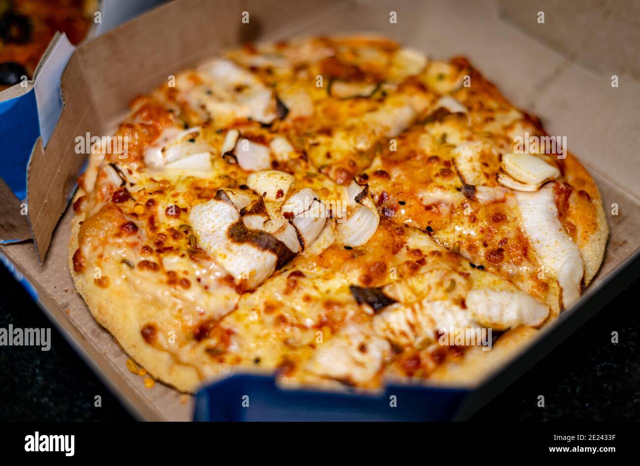 Fuoco selettivo di una pizza vegetariana piccante condita con cipolle e semi di finocchio in una scatola di takeout Foto Stock
