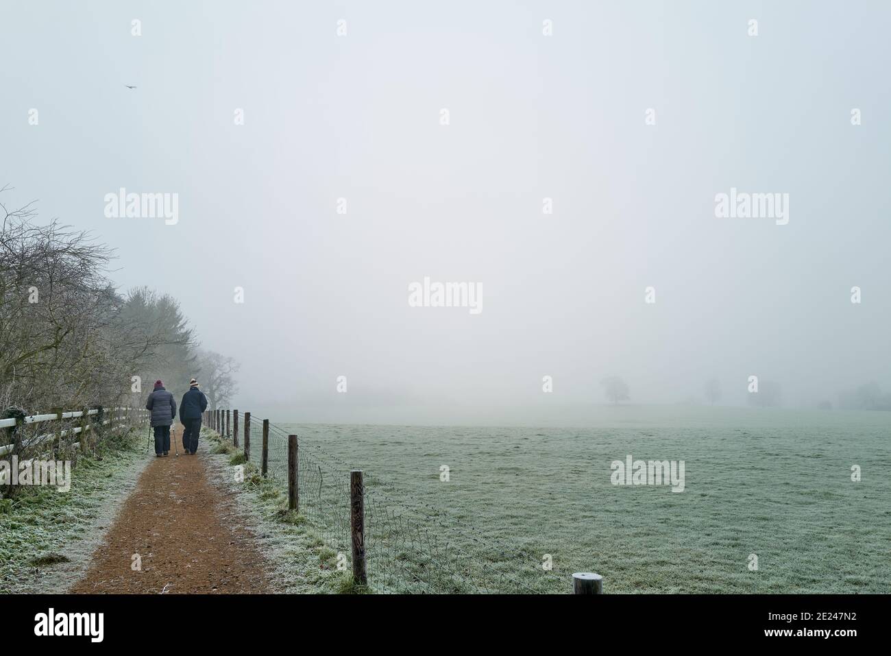 Due rambler camminano lungo il percorso Jurassic Way accanto all'East Carlton Park, Corby, Nhants, Inghilterra, in un giorno di gennaio foggoso durante il periodo di chiusura 2021 Foto Stock