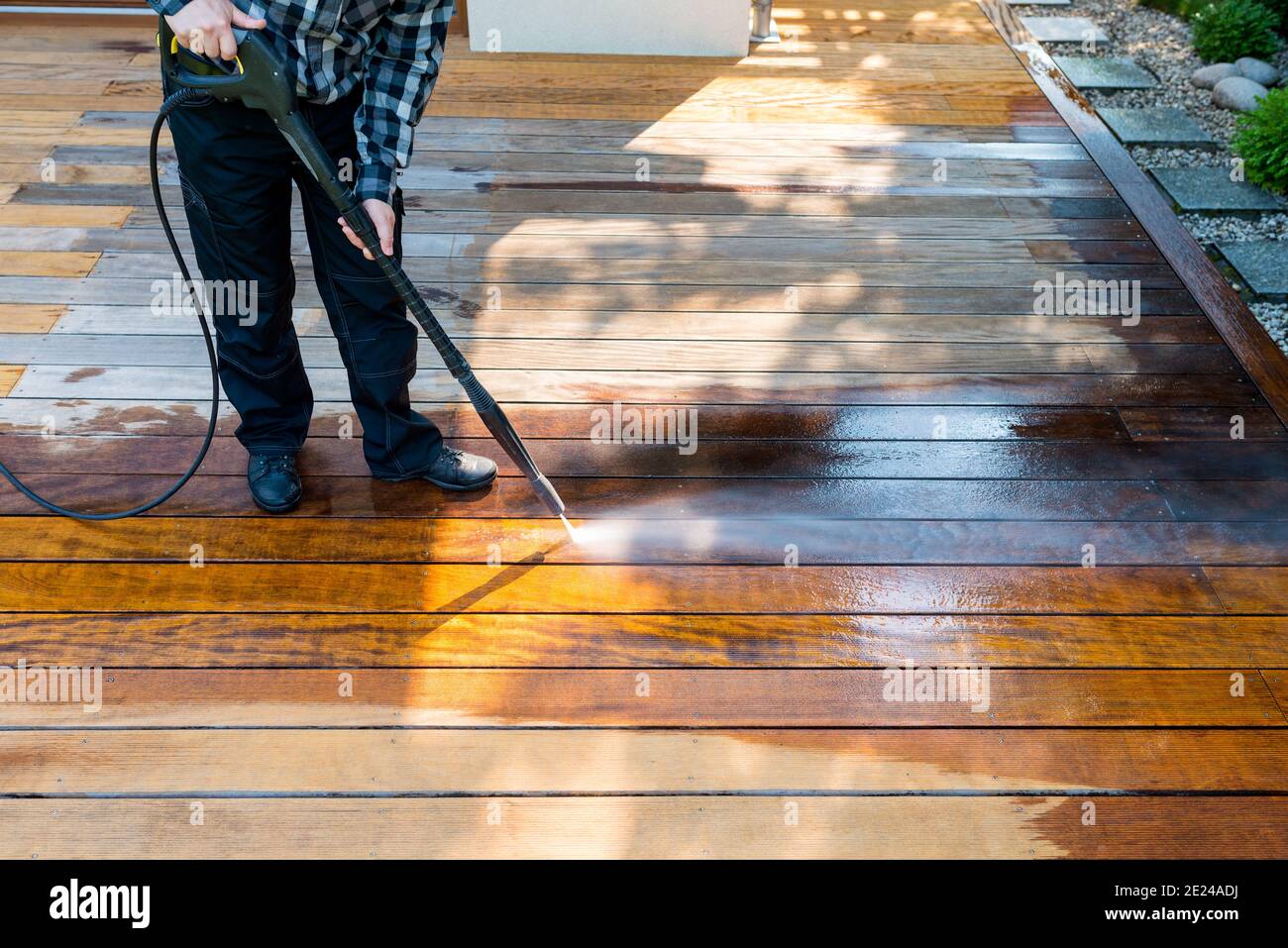 lavaggio a potenza - pulizia uomo terrazza con una lavatrice - pulitore ad alta pressione dell'acqua su superficie in legno Foto Stock