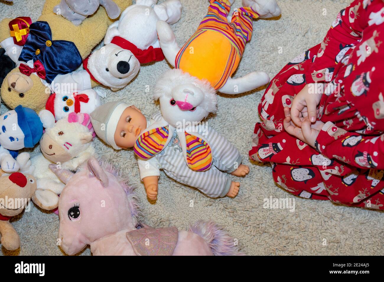 diversi tipi di peluche morbidi giocattoli sul pavimento ovunque nella stanza di un bambino con un gilrl che gioca con loro Foto Stock