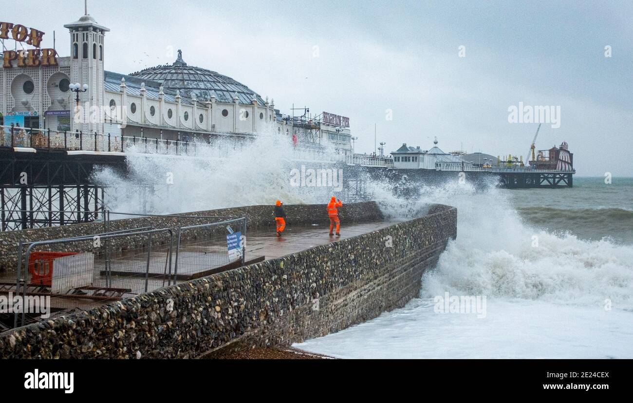 Brighton UK 12 gennaio 2021 - lavoratori di manutenzione ottenere imbevuti sul groyne di Albion da Brighton Palace Pier come le onde si schiantano sopra questa mattina in tempo umido e ventoso lungo la costa meridionale : Credit Simon Dack / Alamy Live News Foto Stock