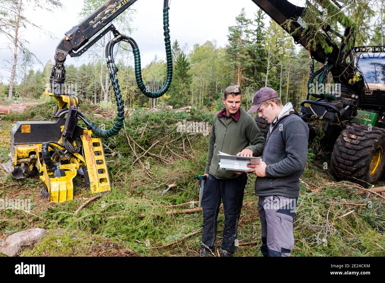 Uomini che parlano di fronte alla macchina forestale Foto Stock