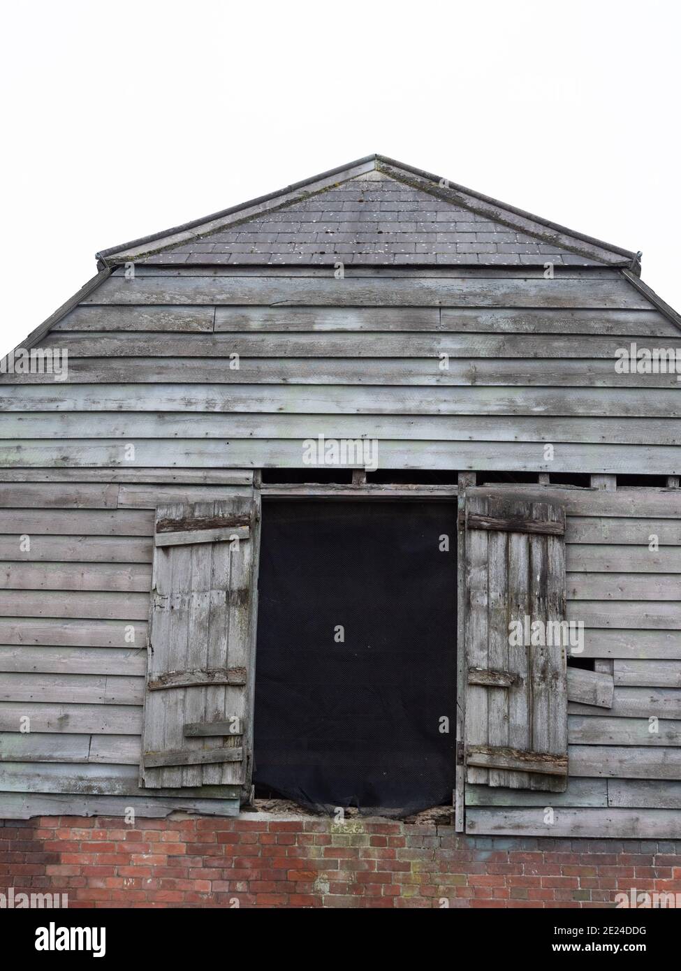 Vecchio fienile in mattoni e legno con porte di carico al primo piano a Westbury, Wiltshire, Inghilterra, Regno Unito. Foto Stock