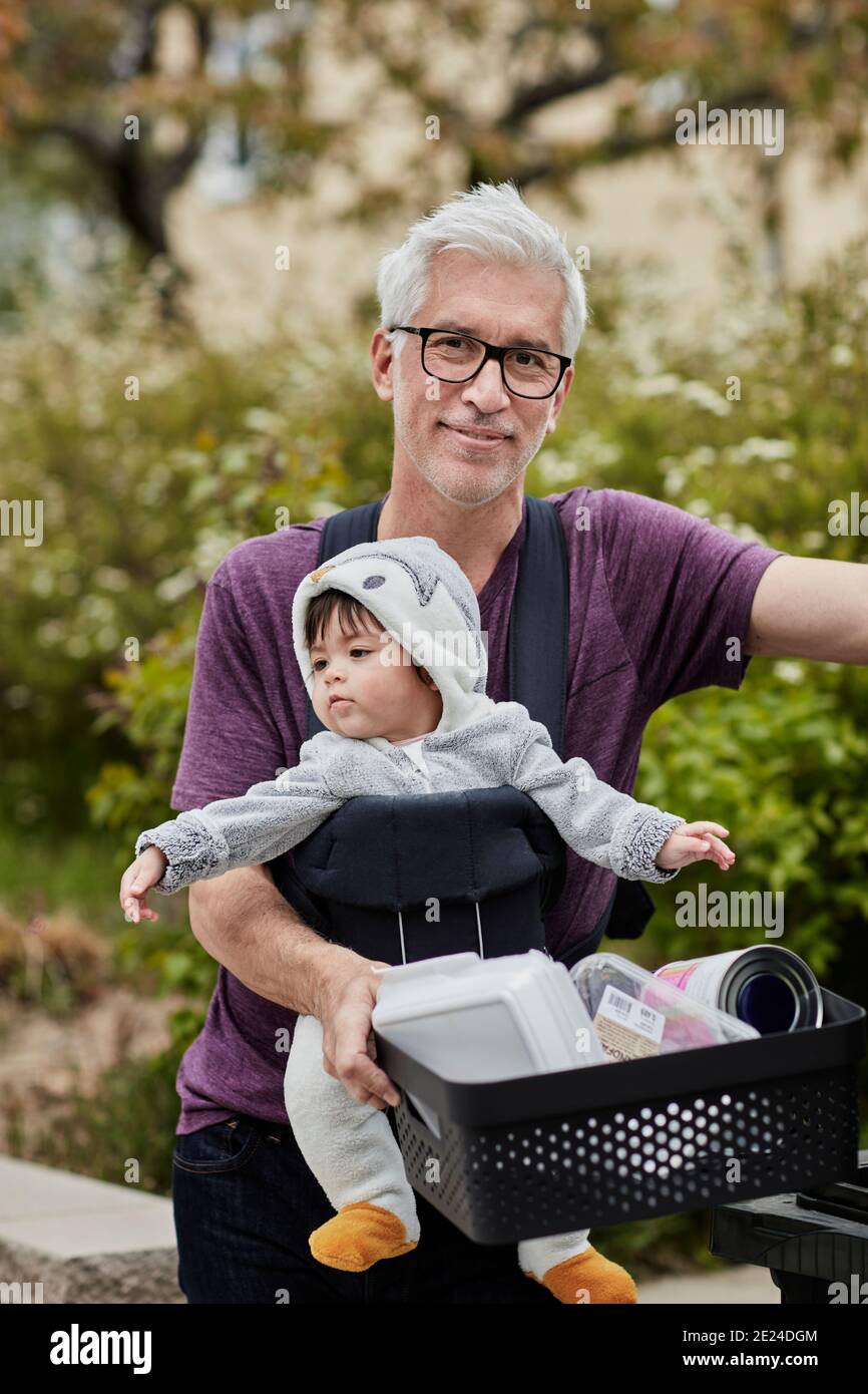 Uomo maturo sorridente con il bambino che trasporta il riciclaggio Foto Stock