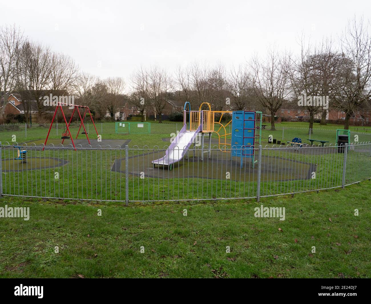 Un parco giochi per bambini deserto in una giornata opaca e sovrastato su Leigh Park Estate, Westbury, Wiltshire, Inghilterra, Regno Unito. Foto Stock