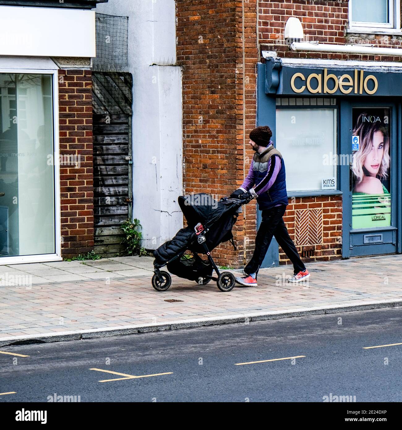 Londra UK, Young Man o Padre da solo spingendo UN bambino o un bambino in UN passeggino lungo una High Street vuota durante il Covid-19 Pandemic Lockdown Foto Stock