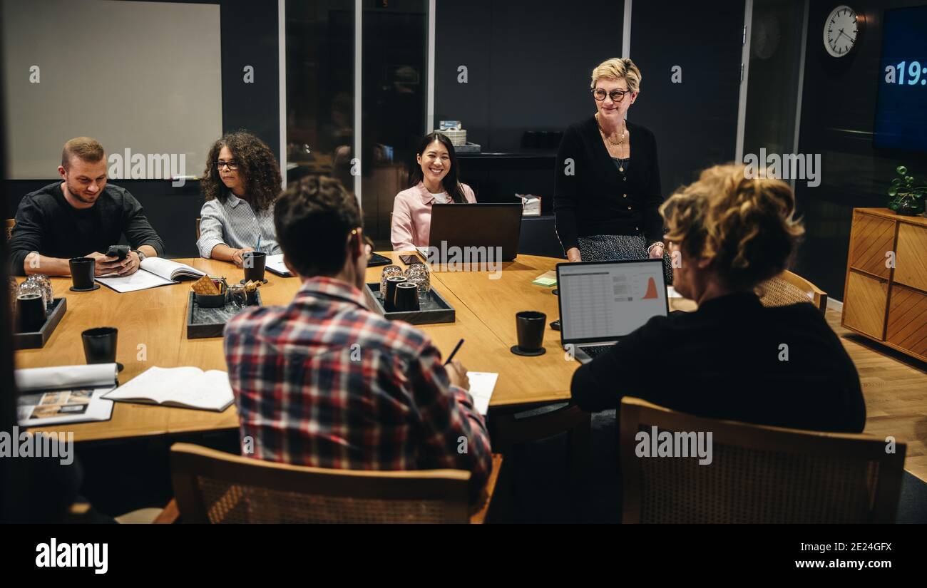 I lavoratori in ufficio discutono insieme di un nuovo piano aziendale nella sala conferenze. Gruppo di uomini e donne in sala riunioni. Foto Stock