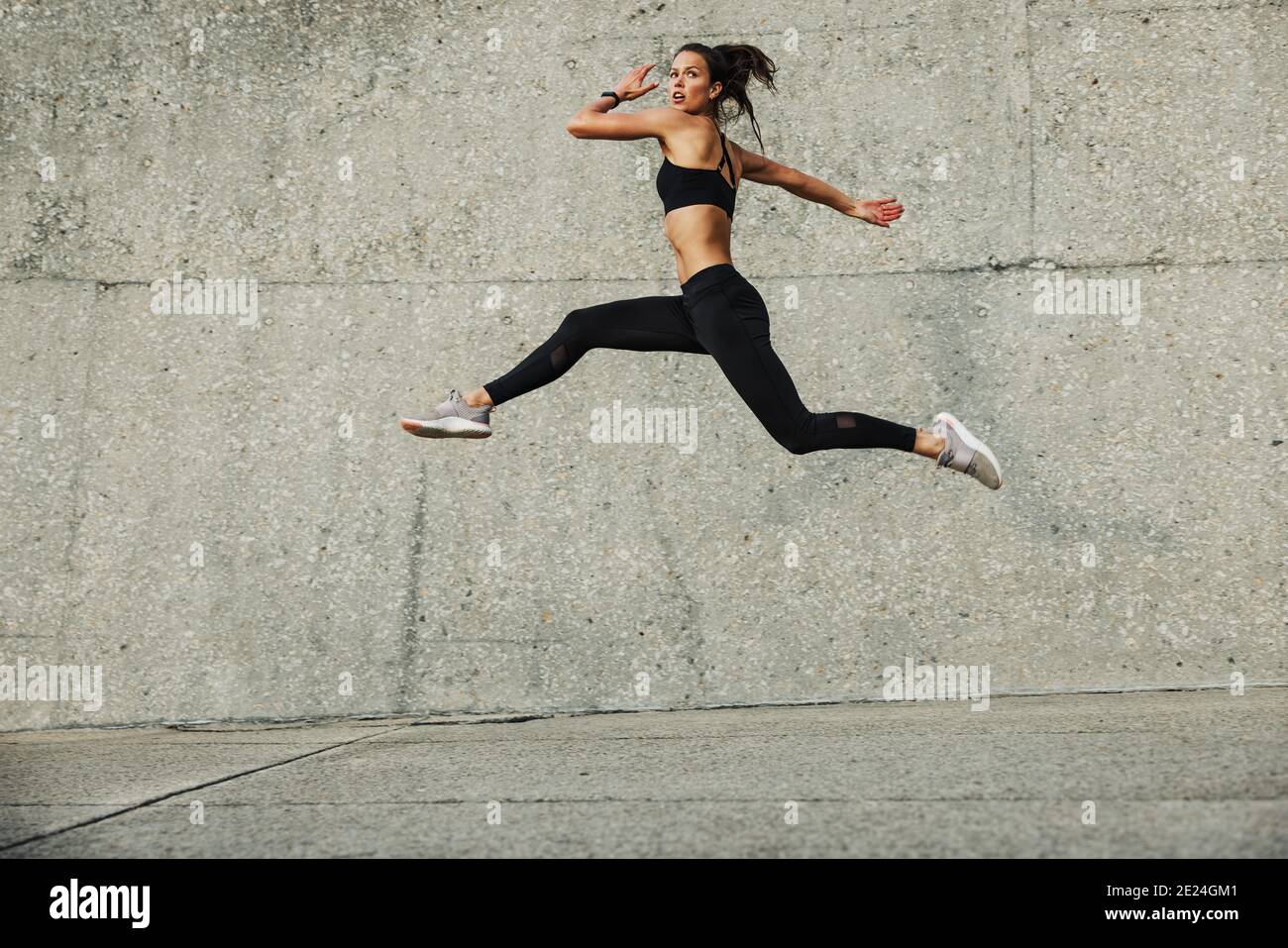 Donna sportiva che fa correre e saltare l'esercizio all'aperto. Fitness atleta femminile che si esercita all'aperto. Foto Stock