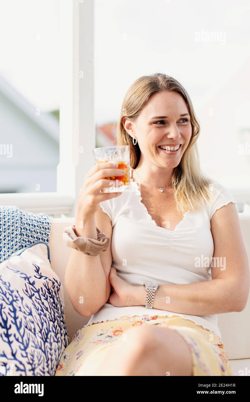 Donna sorridente che beve Foto Stock