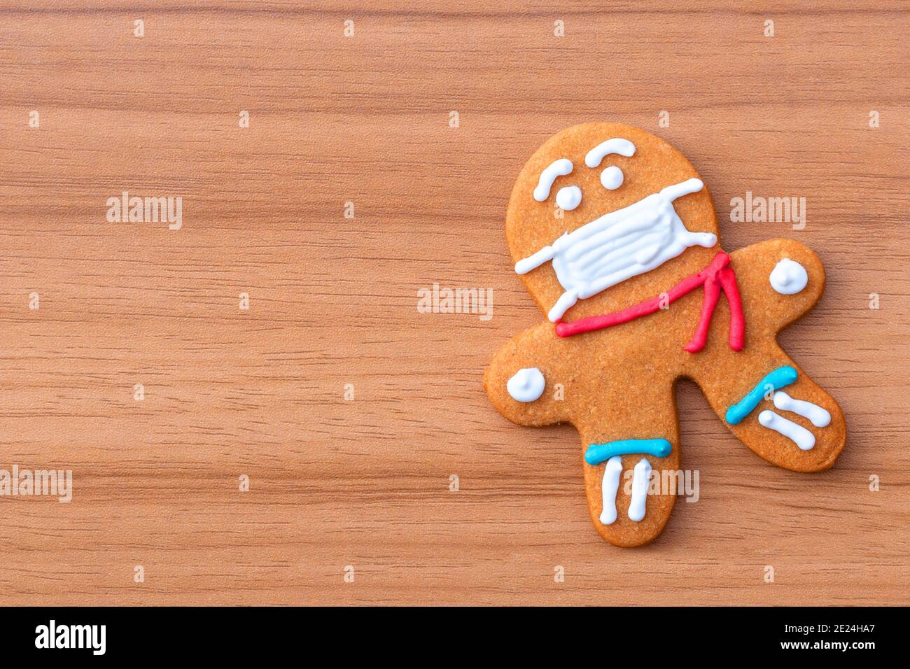 Biscotti classici di pan di zenzero uomo con una maschera medica sul tavolo. Un biscotto uomo di pan di zenzero a forma di uomo con glassa colorata. Foto Stock