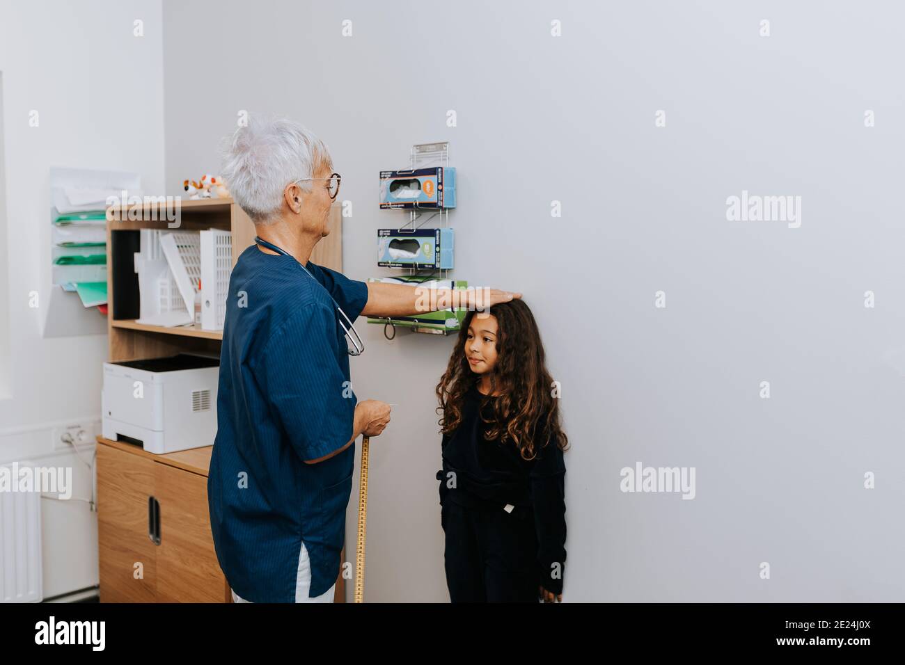Medico che misura la ragazza in ufficio Foto Stock