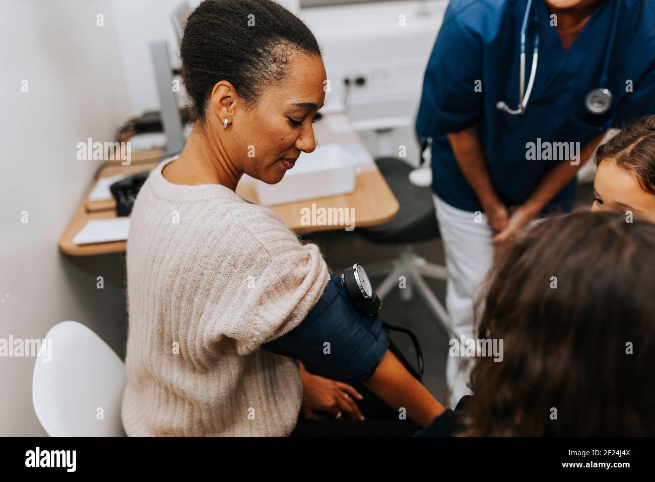 Donna in ufficio medici che controlla la pressione sanguigna Foto Stock