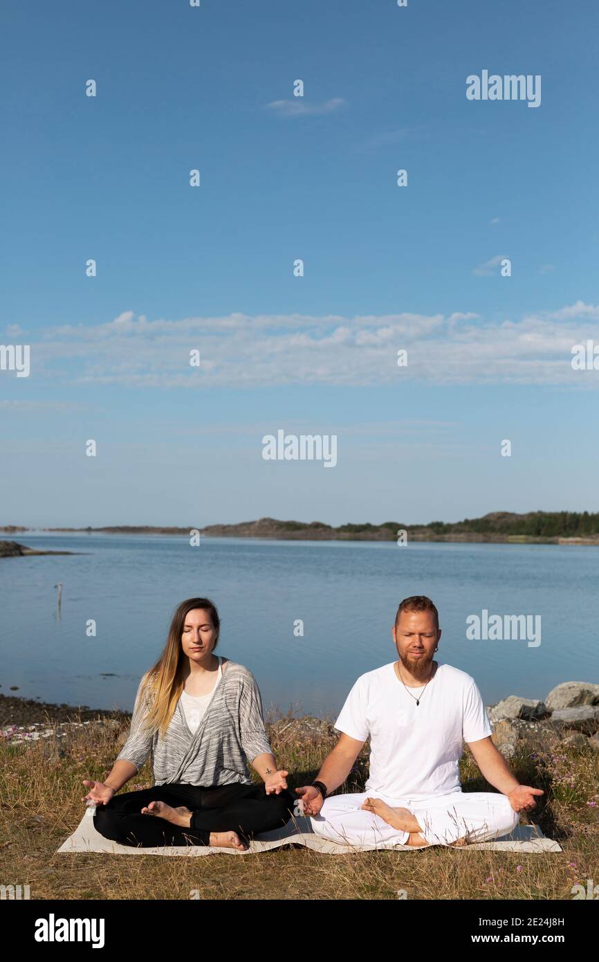 Uomo e donna che meditano in mare Foto Stock